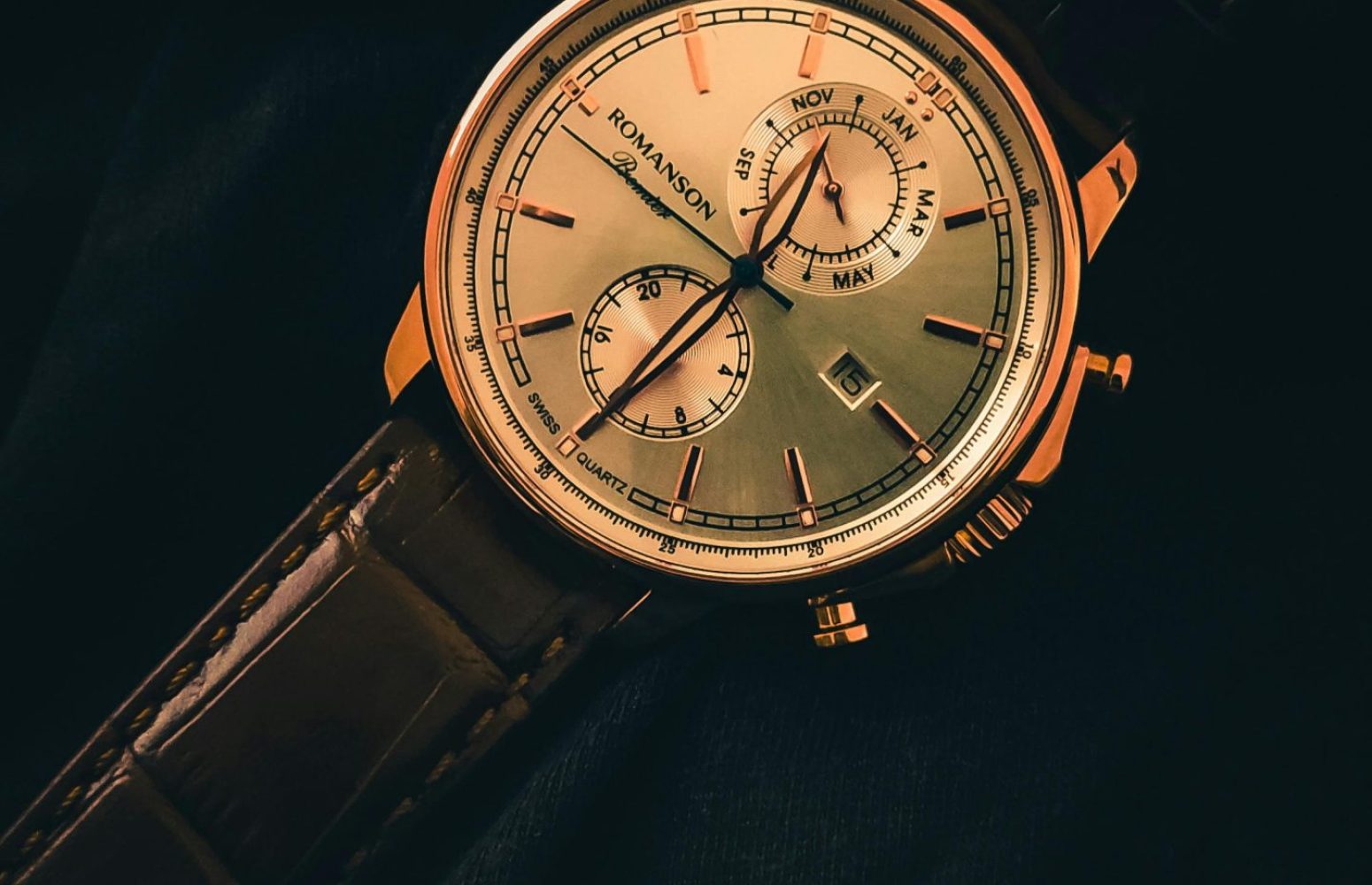 Close-up of a vintage analog wristwatch with a gold dial and leather strap.